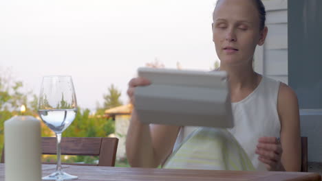 Woman-using-pad-and-drinking-water-in-outdoor-terrace