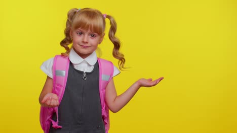 sonriente niña de escuela linda con mochila mirando el espacio de copia para el contenido promocional de la mano