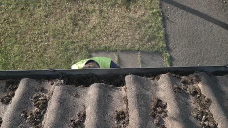 Man-wearing-high-vis-jacket-and-latex-gloves-climbs-up-cleans-roof-gutter