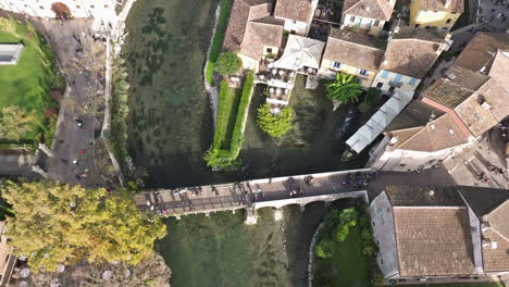 aerial drone view of san marco bridge with tourists crossing in borghetto, valeggio sul mincio, veneto, italy, europe