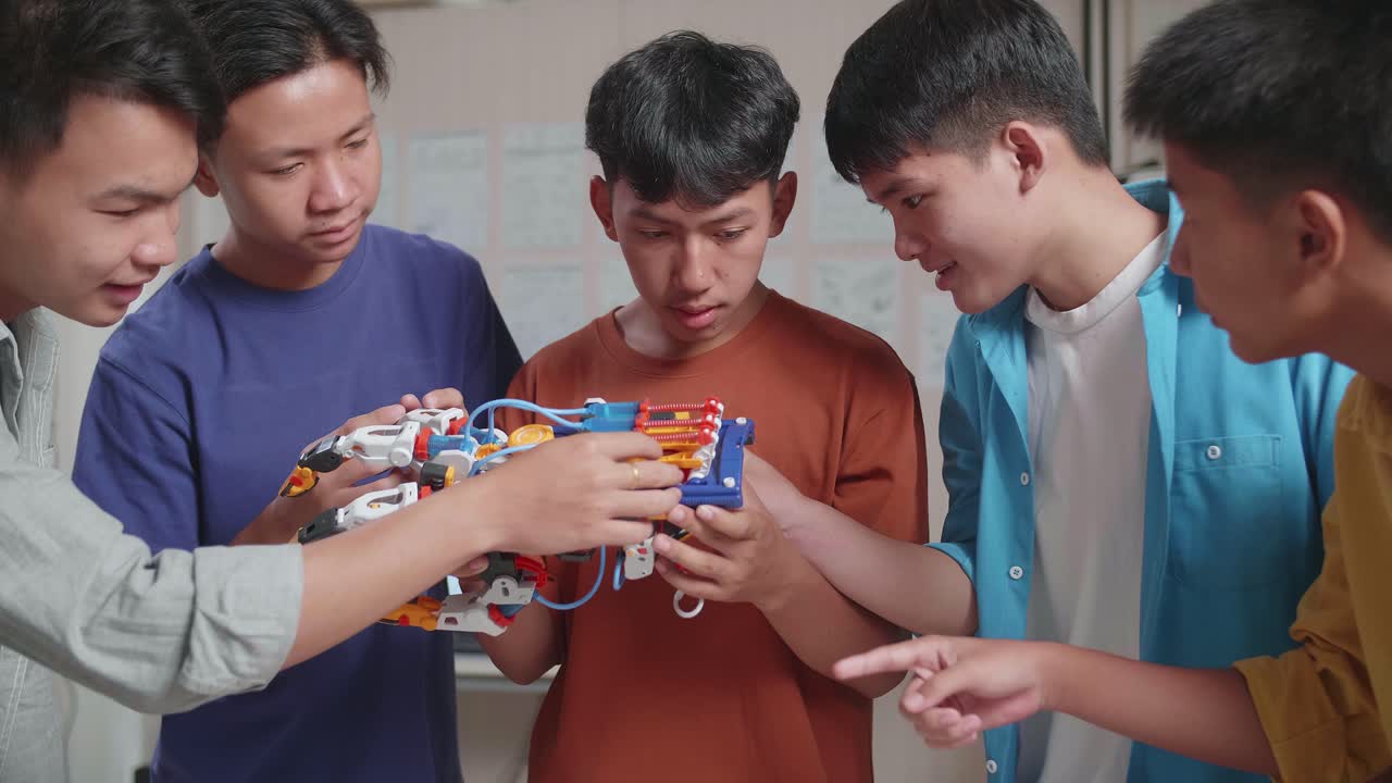 3d 프린팅으로 사이보그 손을 노트북의 사진과 비교하고 집에서 일하면서 웃는 젊은 아시아 소년 그룹.