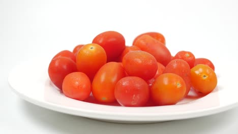 tomate de cereza rojo en un plato sobre fondo blanco