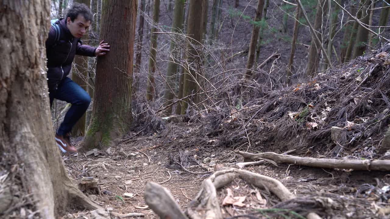 배낭을 메고 숲이 우거진 산길을 걷고 있는 청년 - 클로즈업 샷