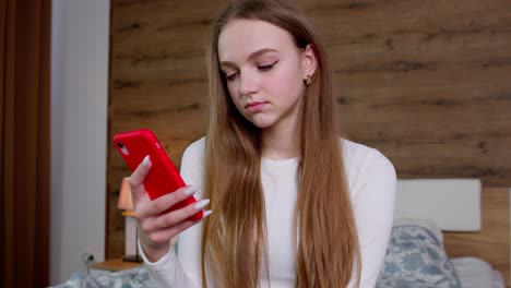 young woman looking at her phone in bedroom