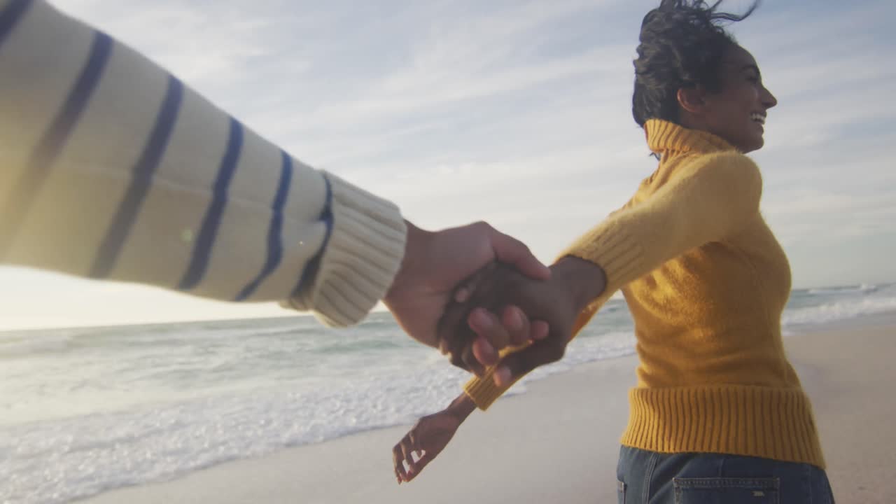 una feliz pareja hispana corriendo y divirtiéndose en la playa