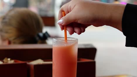 hand stirring a drink with a straw