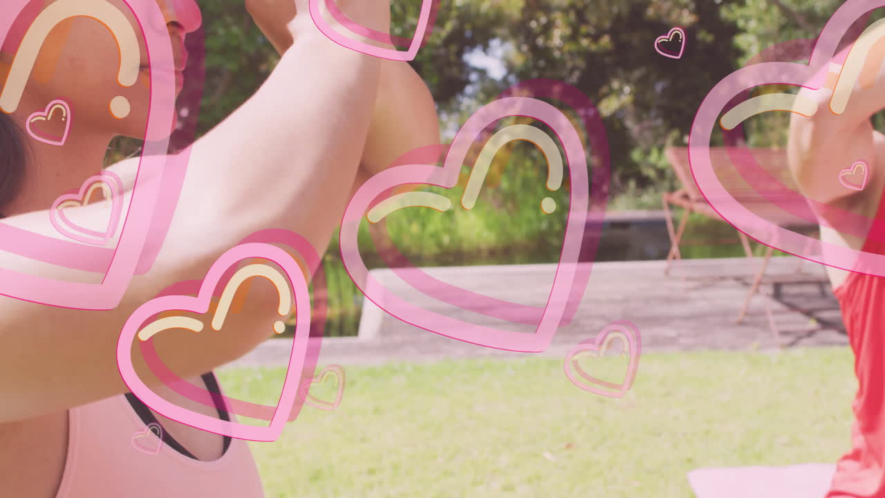 People practicing yoga outdoors with pink heart animations overlaying scene