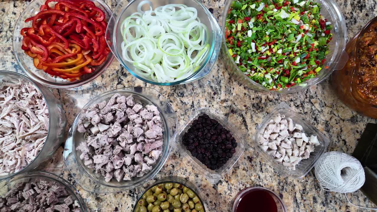 Receita tradicional. De cima para baixo. Ingredientes comuns, como carne moída (de porco e boi), cebolas fatiadas, pimentões vermelhos picados, misturas de especiarias, refogado e o uso de folhas de bananeira.