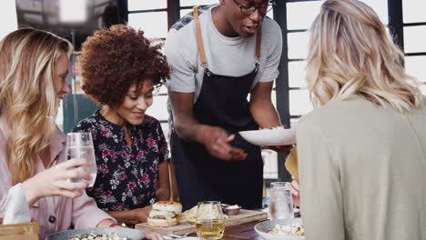 cuatro jóvenes amigas se reúnen para bebidas y comida haciendo un brindis en un restaurante