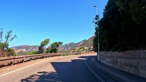 Small-Sardinian-village-landmark,-road-lanes,-vegetation,-rocky-coastline