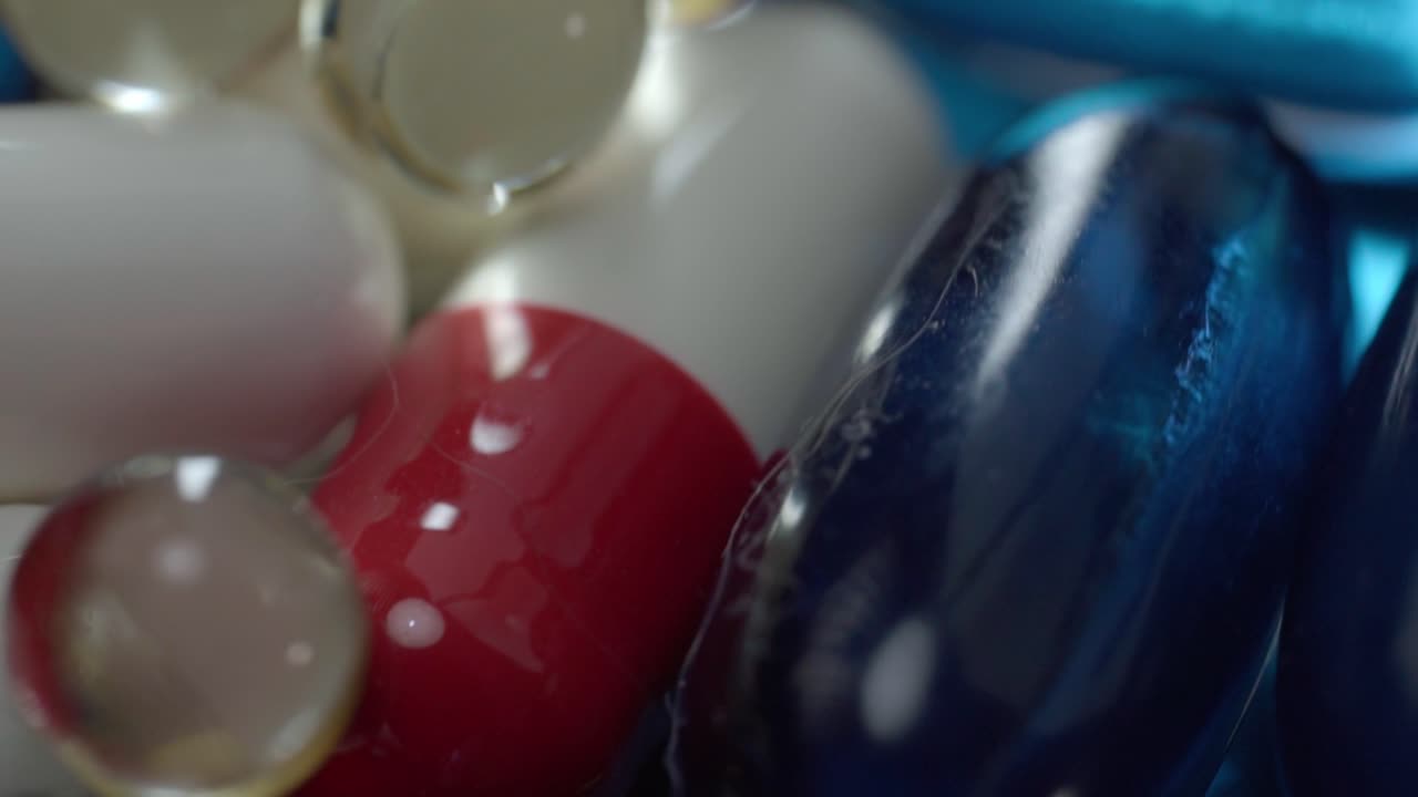 Macro close up shot of red, white, and blue capsules with transparent softgel pills, studio lighting