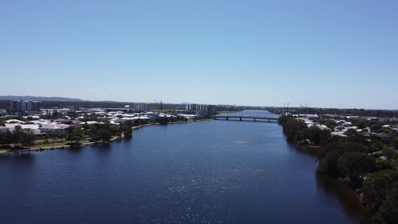 Riprese drone 4K di un canale artificiale con un ponte sullo sfondo e lussuose abitazioni fronte acqua in Australia.