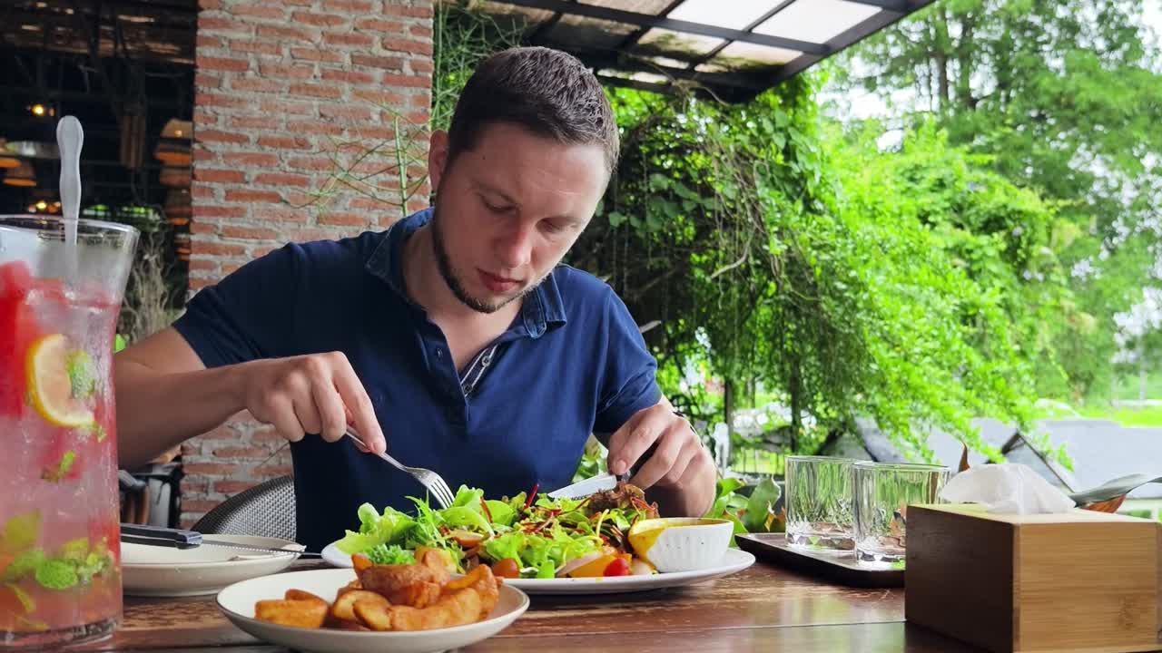 hombre comiendo una deliciosa ensalada en un café al aire libre