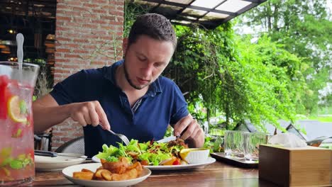 man eating a delicious salad at an outdoor cafe