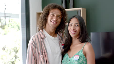 biracial couple at home wearing 'i voted' stickers, highlighting their civic engagement, slow motion