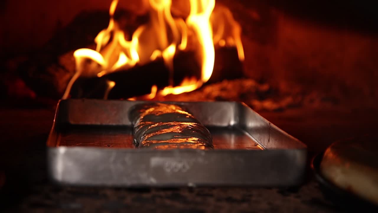Aliments cuisant dans un four traditionnel à bois avec des flammes.