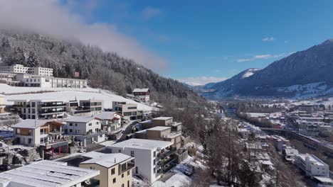 upper class houses and homes on snowy hill in swiss town. beautiful mountain view during sunny day. aerial orbit wide shot. establishing scene. tranquil and quaint atmosphere on cold clear day.