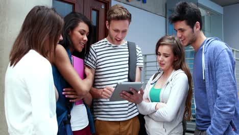 Smiling-friends-standing-and-using-tablet-together