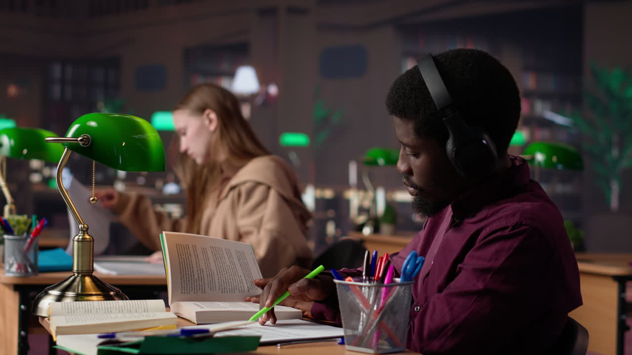 Vertical video male student listening to ambient study music on headset and collecting data
