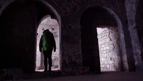 Shadow-and-light:-Male-backpacker-explores-medieval-church-interior