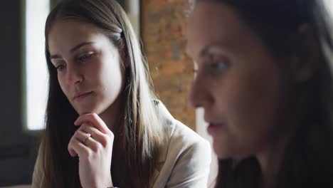 retrato de dos mujeres de negocios caucásicas sentadas a la mesa, hablando, teniendo una reunión de negocios