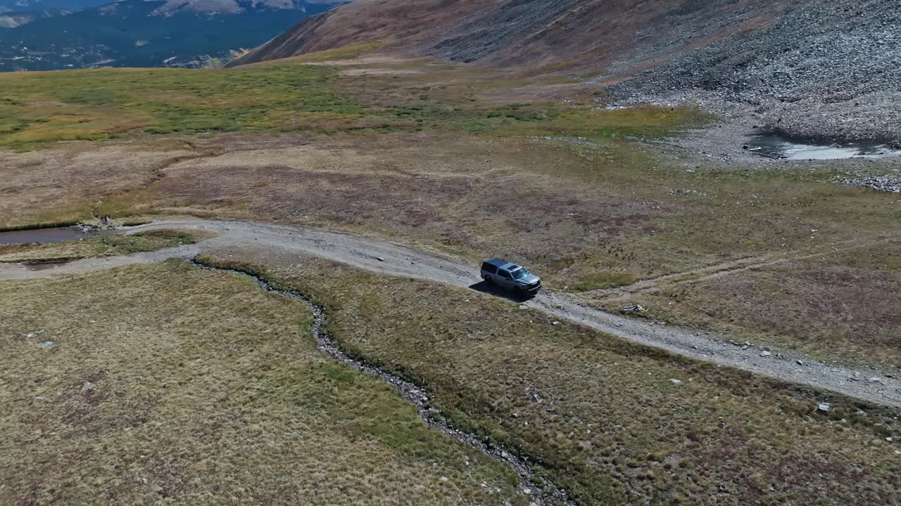Panoramic aerial orbit of truck driving along gravel road on Peak 10 trail Breckenridge Colorado