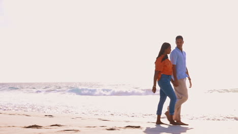 Couple,-holding-hands-and-walk-by-ocean-with-space