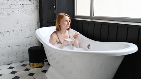 woman chilling in bathtub with cup of drink