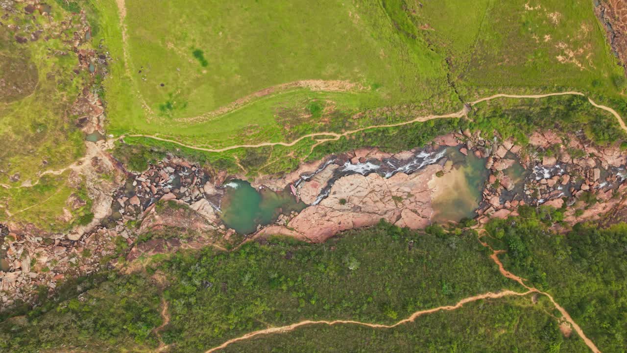 Scenic top down view of a river carving its way through a rocky canyon and lush green fields, colombia