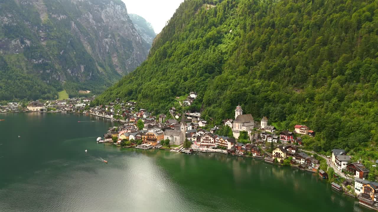 Aerial view of Hallstatt, Austria, captured by drone, showcasing its picturesque lakeside homes, majestic mountains, and the unique charm of this enchanting alpine village.