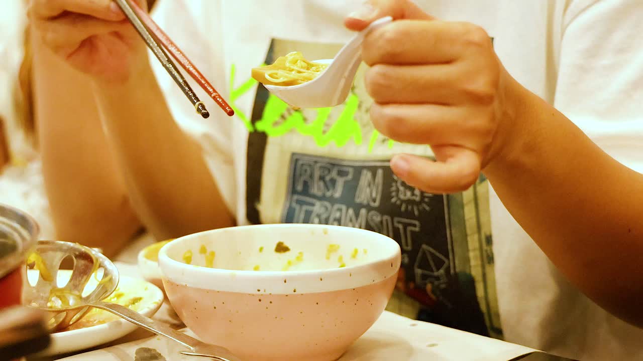 People sharing a meal with chopsticks and spoon