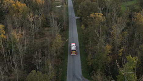 vista di tracciamento aereo del veicolo del camion dei pompieri di emergenza che guida in movimento veloce lungo la strada rurale di campagna con luci lampeggianti, missione di salvataggio del primo soccorritore per avviso di incidente antincendio