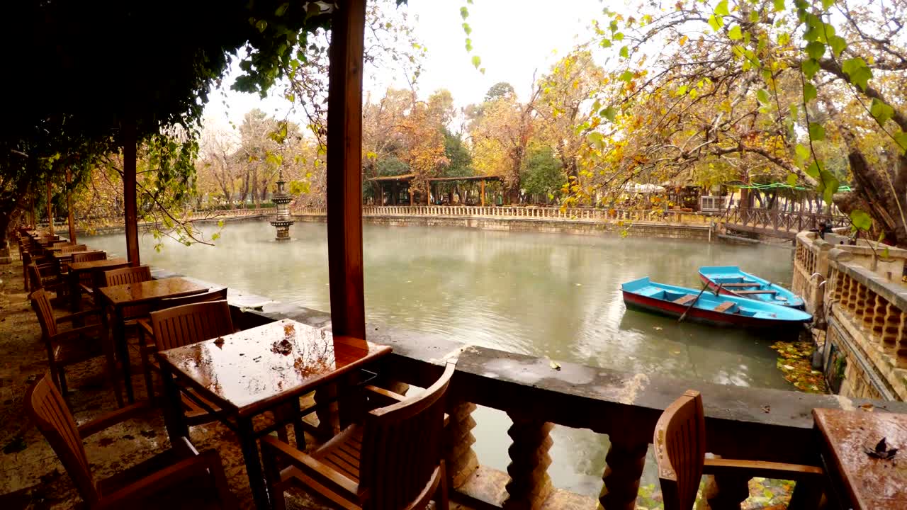 공허한 레스토랑 두 개의 파란색 보트 무어 안개는 초록색과 노란색 나무 주변의 분수와 연못 아래에 떠 있습니다.