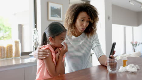 Madre-Birracial-Preocupada-E-Hija-Enferma-Teniendo-Videollamada-Con-Un-Médico-En-Un-Teléfono-Inteligente,-Cámara-Lenta