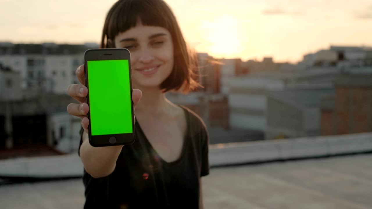 atractiva morena con gadget en el techo al atardecer