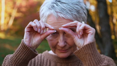 senior woman demonstrating small size with hand gesture outdoors