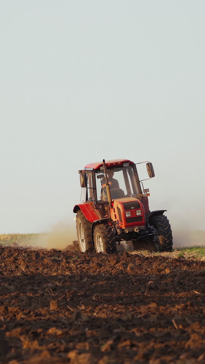 Tractor plowing fields, preparing land for sowing. Farmer in tractor preparing land in farmlands outdoors. Agricultural industry. Vertical video