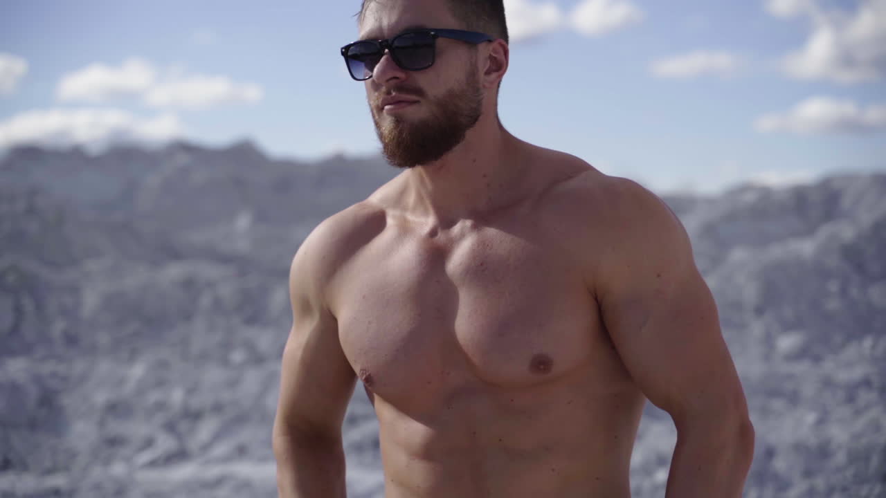 Bearded sportsman in sunglasses. Shirtless guy with muscular body on white canyon background. Healthy bodybuilder outdoors.