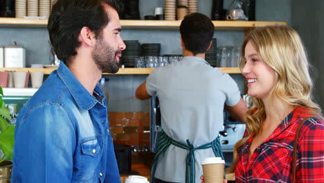 young couple interacting and holding disposable coffee cup