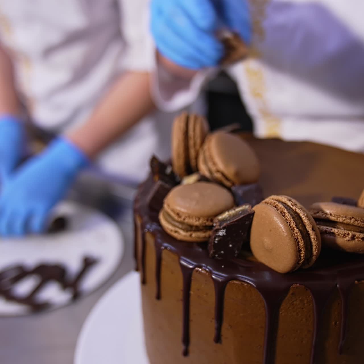 Tasty chocolate cake beautifully decorated in the food factory. Pastry professionals put the sweets on top of the big cake. Close up