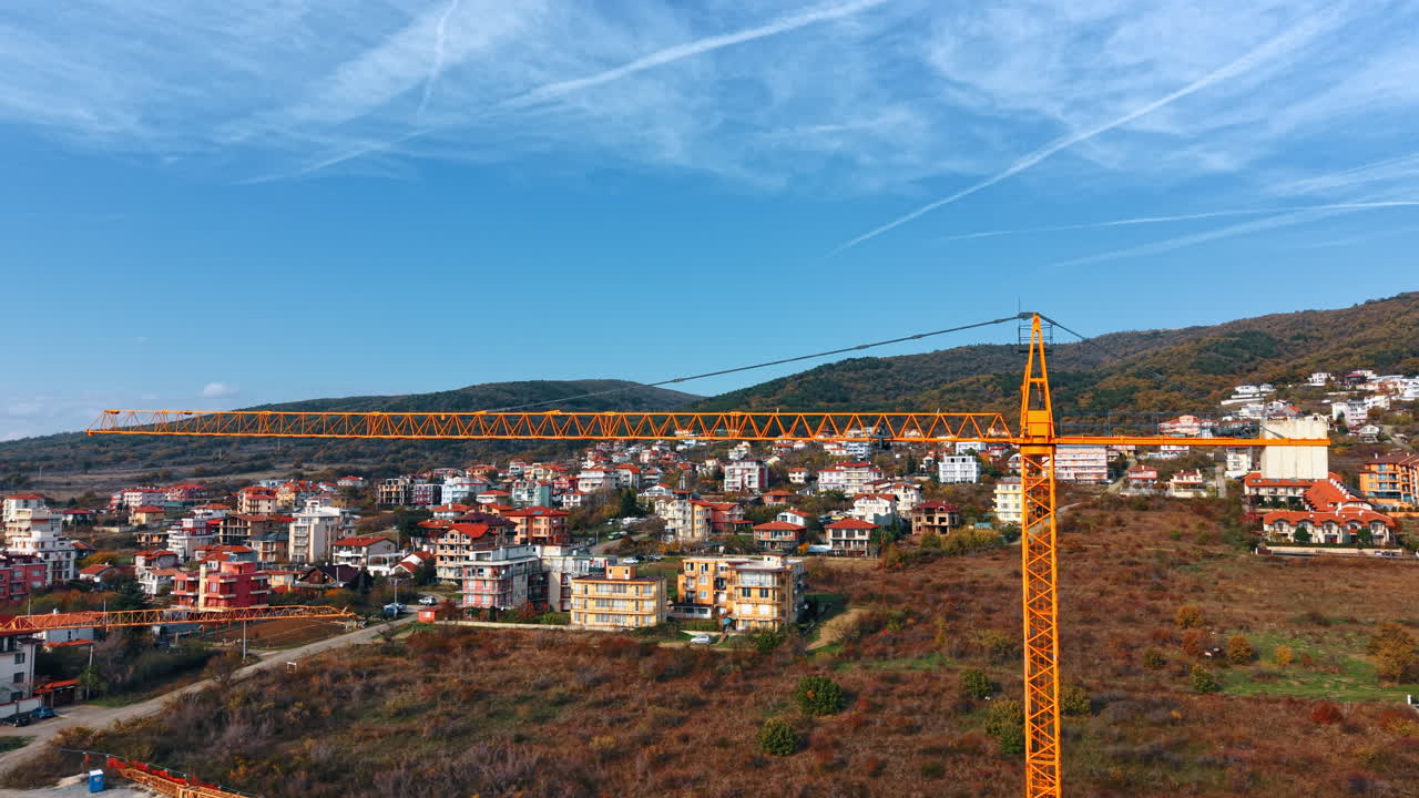 Riprese del braccio di una gru che si erge in un'area montuosa. Diverse ville si trovano sul pendio sullo sfondo.