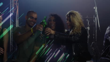 friends clinking green beer bottles in nightlife scene, featuring light beams and metal trusses