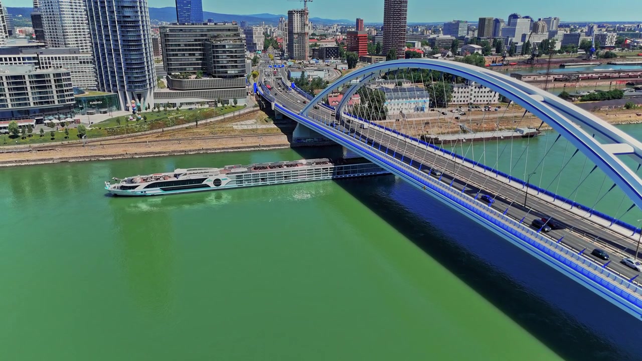 Udsigt fra Bratislava med en båd, der passerer under en moderne bro på Donau-floden