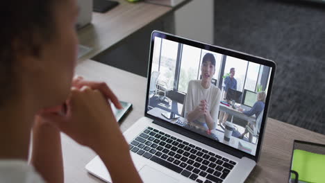 african american woman having a video conference on laptop with female office colleague at office