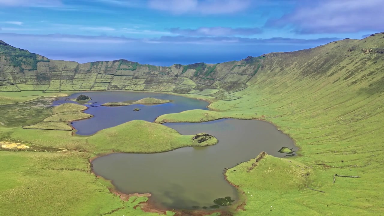 青い空の下、湖と急な斜面がある緑の火山クレーターの空撮。