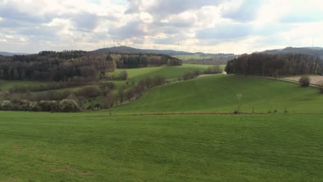 Ascending-over-green-lushes-hill-side-in-Germany-with-traffic-on-a-winding-road