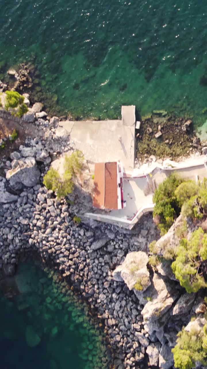 Vertical top-down aerial shot capturing a small islet near Parga, Greece, surrounded by turquoise waters and anchored boats