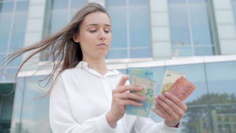 young attractive business woman counting a wad of bills on the office outdoors