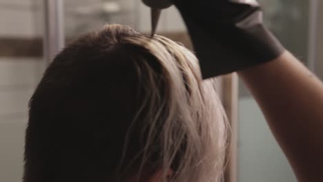 aplicar lejía para el cabello en la sección media de la cabeza - toma de primer plano