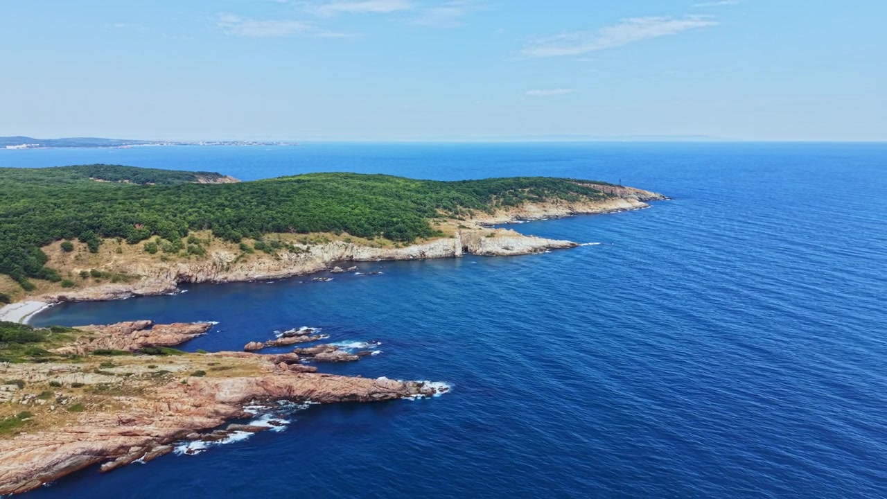 Vista costiera con acqua, rocce e alberi in una giornata limpida vicino a una zona costiera.